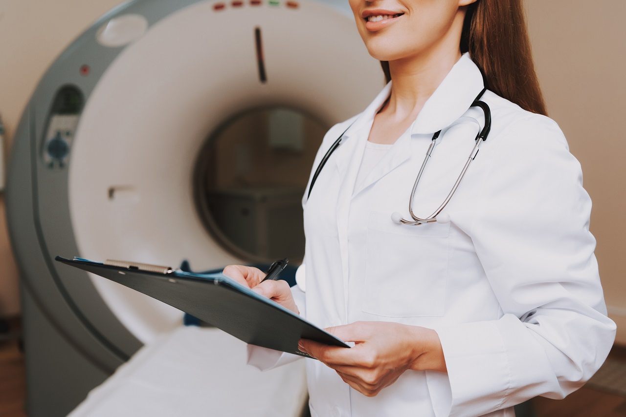Close up of a female doctor holding a clipboard in front of an MRI machine