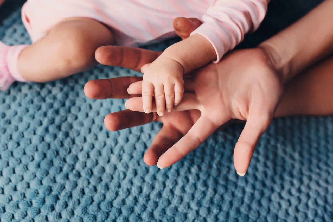 Close up of a parent's hand being held by their newborn child