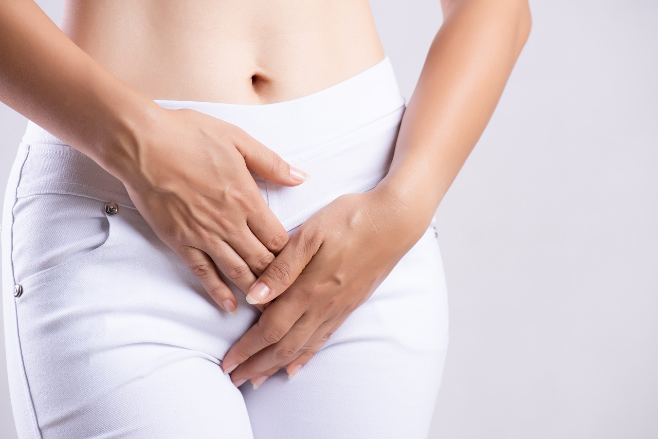 Close up of a young woman clutching her stomach in pain