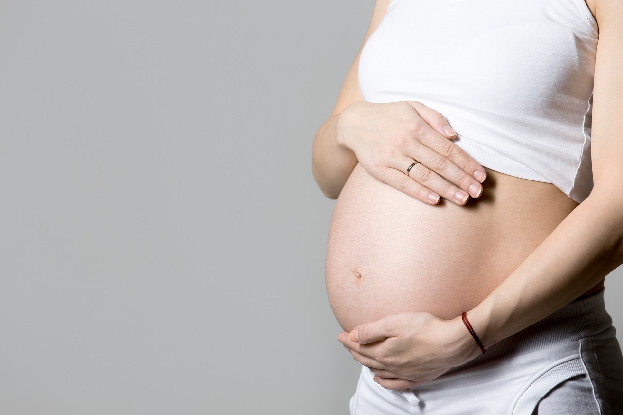 A pregnant woman clutching her pregnant belly