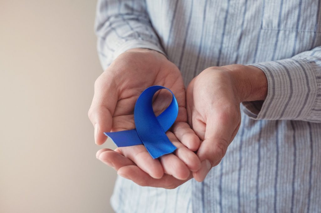 A man holding a blue ribbon, signifying the fight against prostate cancer