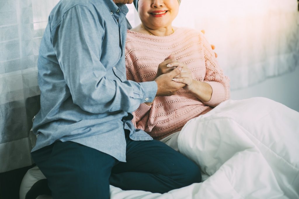 An elderly woman with cancer hugging her husband