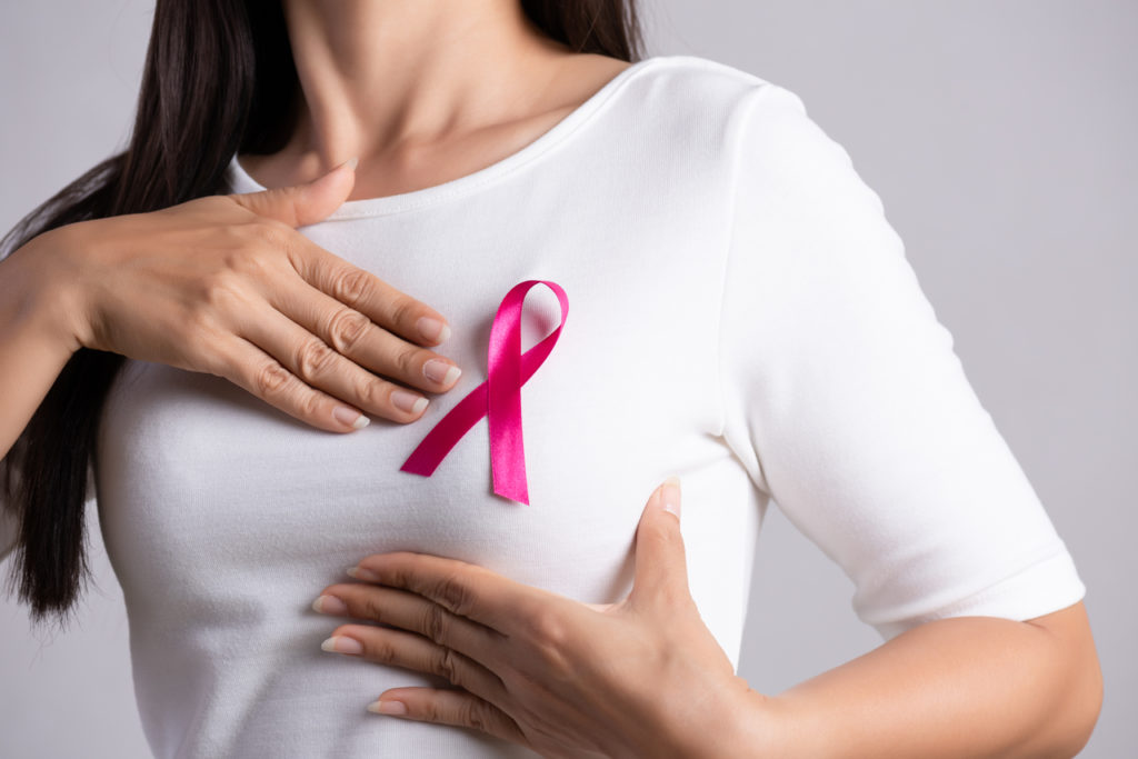 A woman in a white shirt with a pink ribbon on her breast area