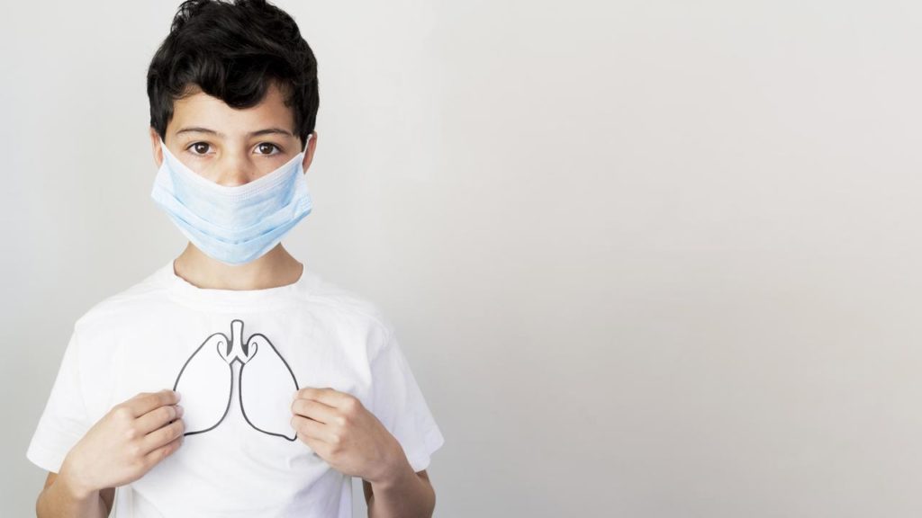 A boy in a face mask showing the effect of COVID-19 on the lungs